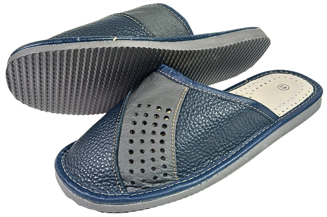 Men's leather slippers pair showing flexible rubber sole and perforated cowhide upper, handmade in Poland